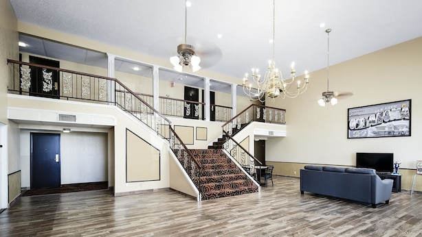 A spacious lobby with a grand staircase, a chandelier, and a blue sofa.