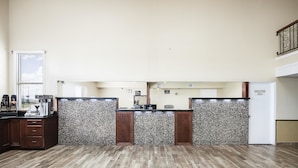 A reception area with a wooden floor, a counter with a coffee machine, and a sign that reads "EMPLOYEES ONLY".