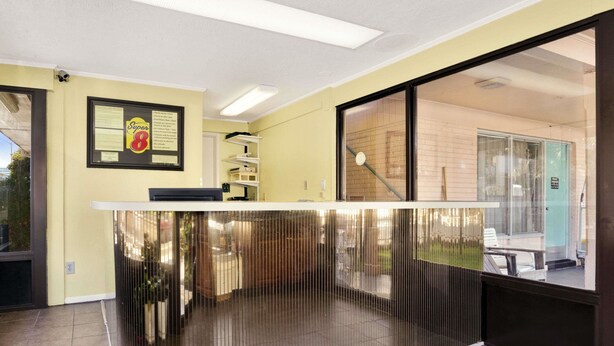 A reception area with a counter, a framed notice on the wall, and a view of the outside through a glass door. - Royal Palace Inn & Suites (Myrtle Beach)