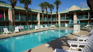A swimming pool with lounge chairs and palm trees. - Royal Palace Inn & Suites (Myrtle Beach)