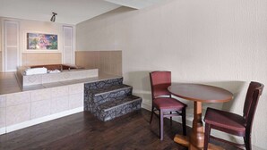 A bathroom with a bathtub, a sink, and a shower. There is a painting on the wall and a step leading to the bathtub.