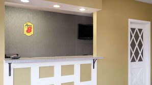 A reception area with a counter, a television mounted on the wall, and a door with a lattice design.