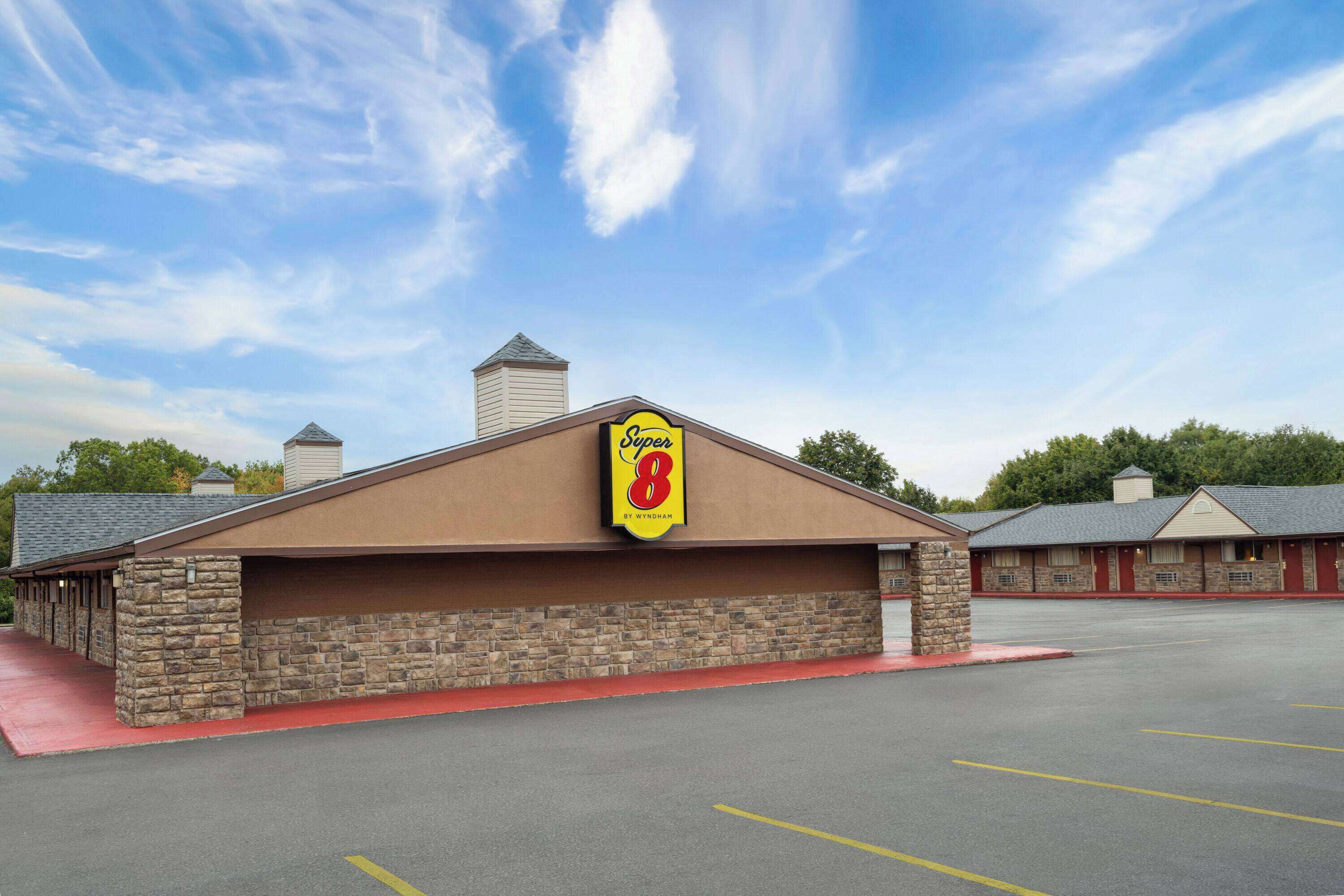 A Super 8 motel with a stone facade, a red awning, and a parking lot.