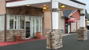 A building with a stone facade, large windows, and a covered entrance area with a red awning.