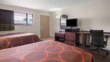 A hotel room with two beds, a desk, a chair, a television, and a window with curtains.