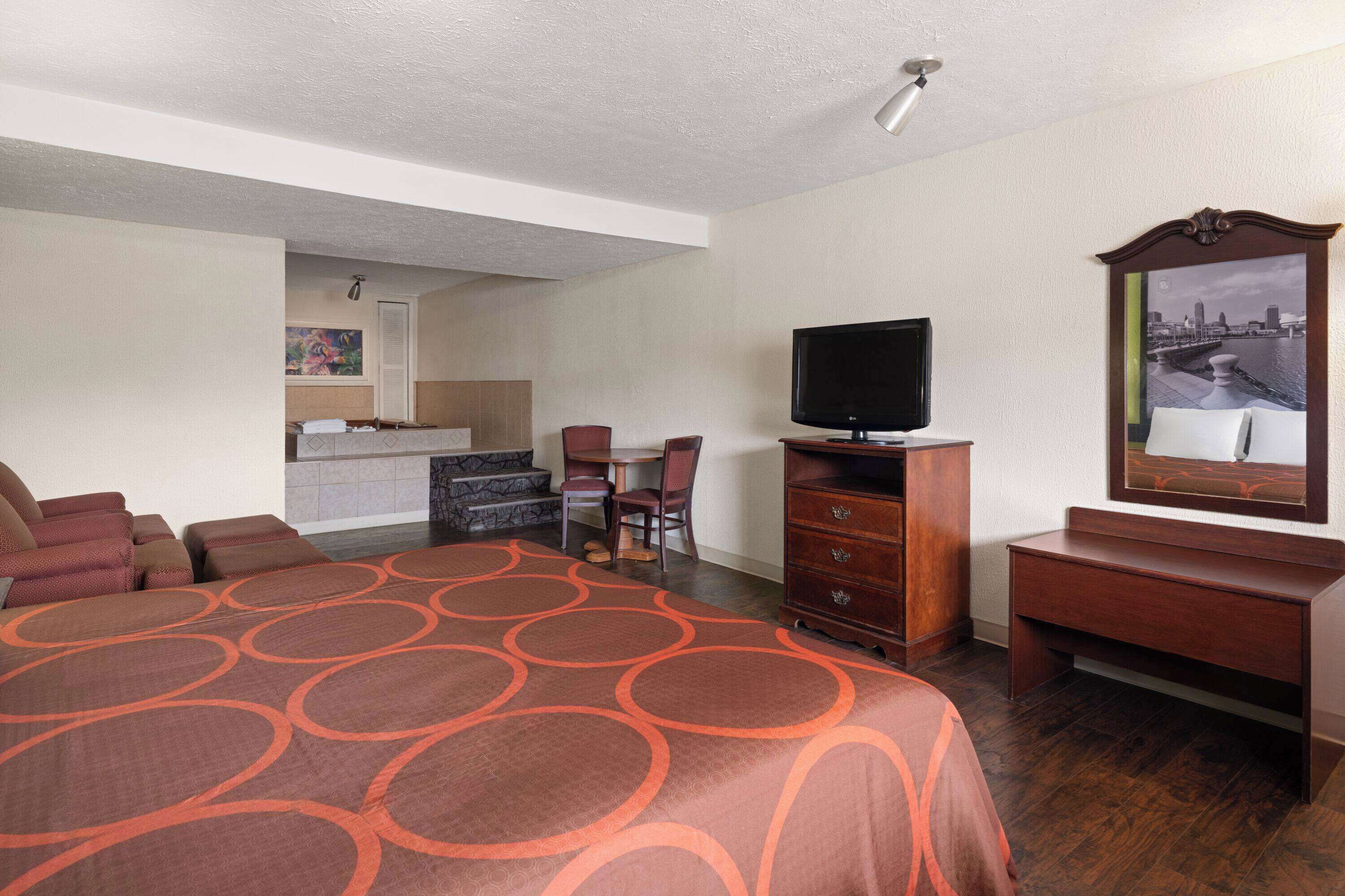 Une chambre d’hôtel avec un grand lit, une télévision, un bureau et une chaise.