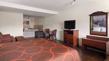 A hotel room with a large bed, a TV, a desk, and a chair.