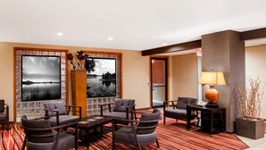 Vestíbulo de hotel con zona de estar, ventanas amplias con vistas panorámicas, mostrador de recepción y una lámpara.