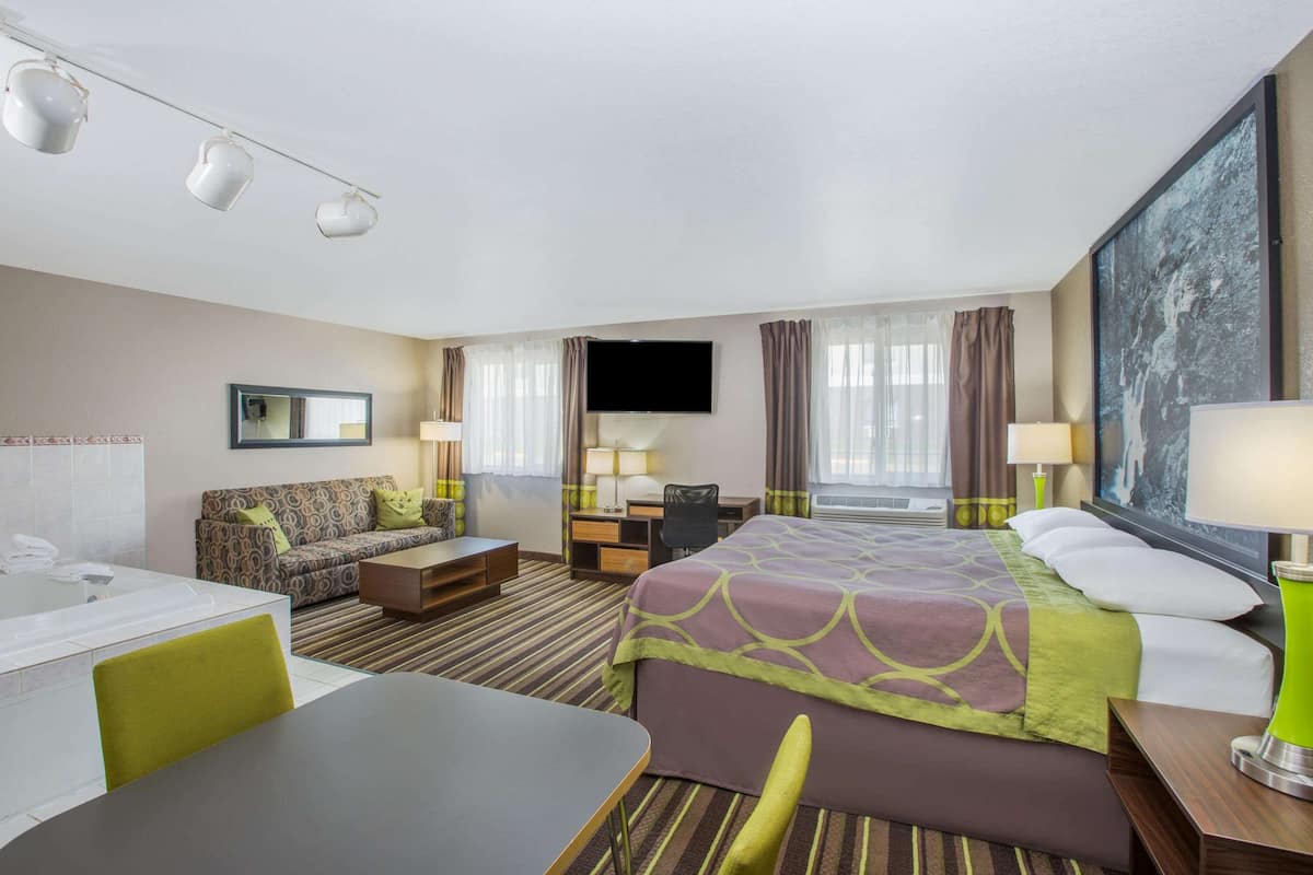 Une chambre d’hôtel équipée d’un lit, d’un bureau, d’une chaise, d’un canapé, d’une télévision et d’une grande fenêtre.
