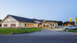 Un hotel con un amplio camino de acceso, un vestíbulo cubierto y un aparcamiento con varios vehículos.