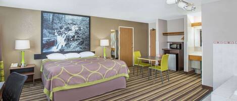 Une chambre d’hôtel équipée d’un lit, d’un bureau, d’une chaise, d’une table et d’un four à micro-ondes.