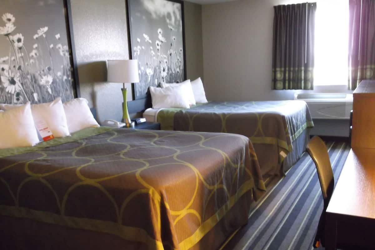 Une chambre d’hôtel avec deux lits, un bureau et une fenêtre avec des rideaux.
