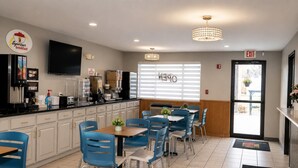 A breakfast restaurant with a counter, seating, and a TV. - Super 8 by Wyndham Warrenton (Warrenton)