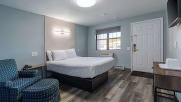 Quarto com cama, cadeira, escrivaninha e janela.