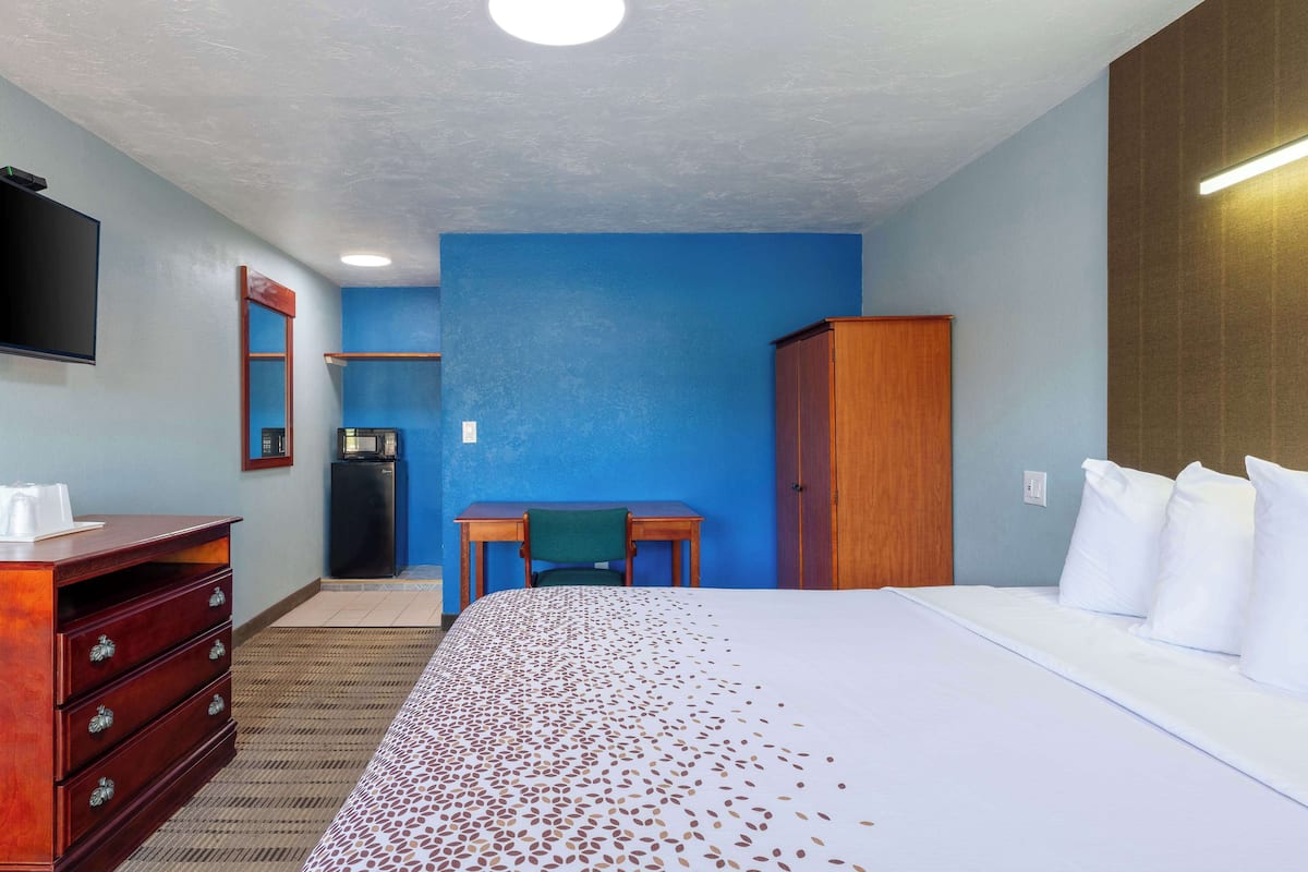 A hotel room with a large bed, a desk, a wardrobe, and a television.