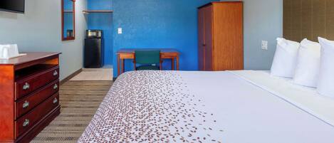 A hotel room with a large bed, a desk, a wardrobe, and a television.