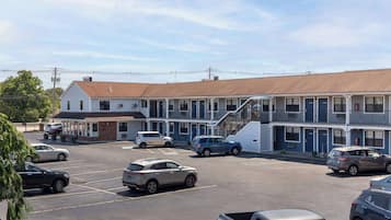 Um motel com vários quartos, estacionamento e um pequeno edifício com área coberta.