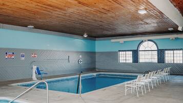 Una piscina interior con techo de madera, paredes de azulejos y una ventana con diseño de ladrillo.