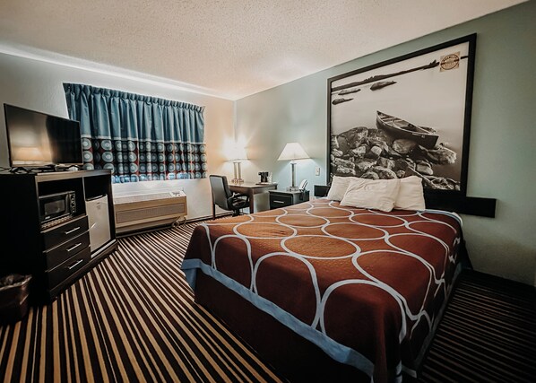 A hotel room with a bed, a desk, a chair, a television, and a window with curtains.