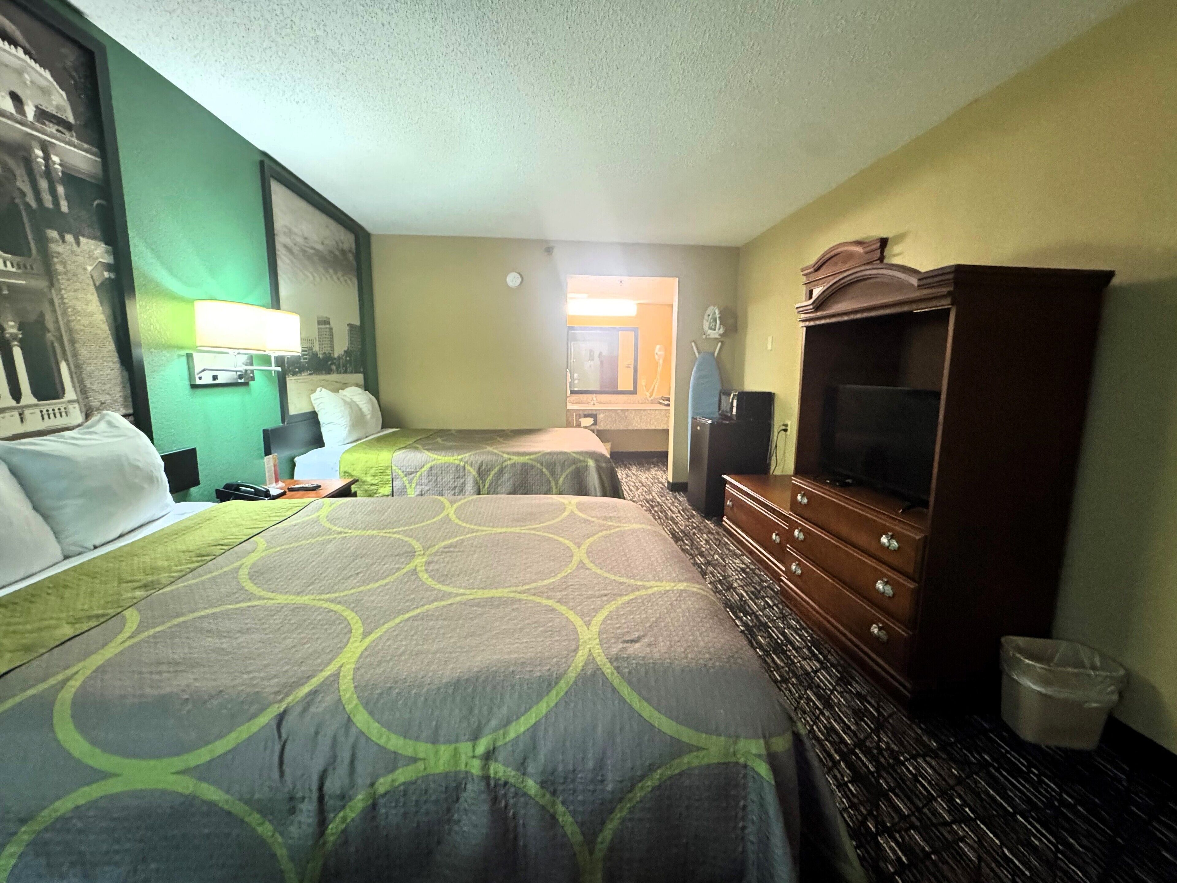 Habitación de hotel con dos camas, un aparador, un televisor y un reloj de pared.