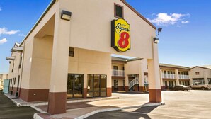 Ett Super 8-hotell med en beige fasad, stora fönster och en tydlig skylt med texten ”Super 8”.
