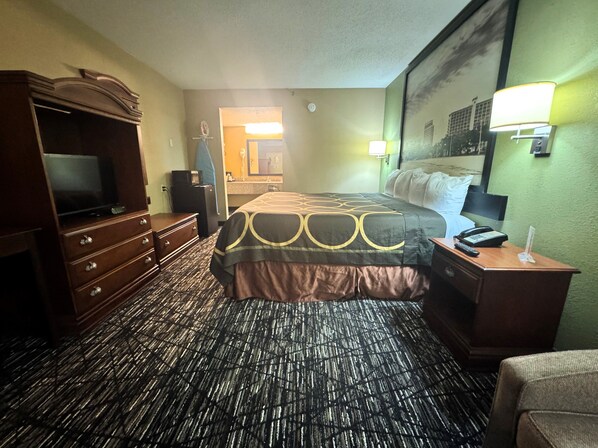 Una habitación de hotel con cama, cómoda, televisión y un cuadro en la pared.