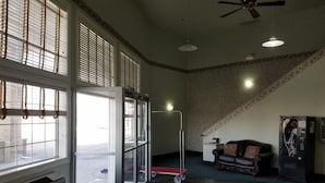 A spacious lobby with large windows, a ceiling fan, a vending machine, and a leather sofa. - Simple Rewards Inn (Guymon)