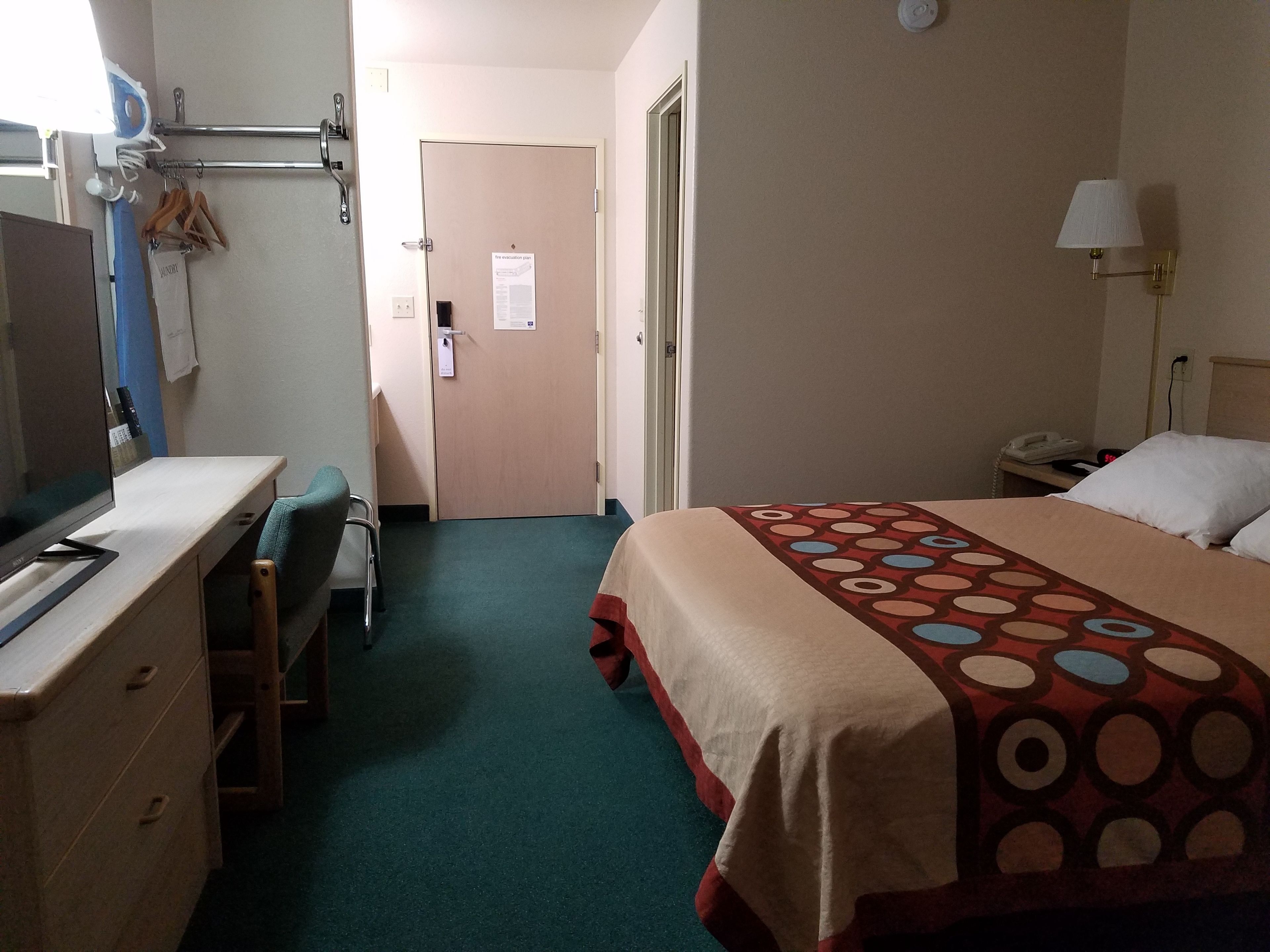 Une chambre d’hôtel équipée d’un lit, d’un bureau, d’une chaise, d’une télévision et d’une salle de bain avec un porte-serviettes.