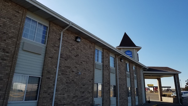 A two-story building with a flat roof and a small triangular structure on the roof. - Simple Rewards Inn (Guymon)