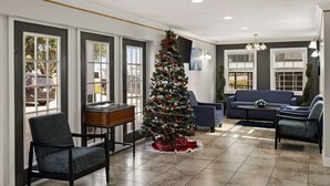 Un salon spacieux avec un grand sapin de Noël, des sièges confortables et de grandes fenêtres.