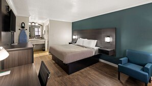 Une chambre d’hôtel comprenant un lit, des tables de chevet, un bureau, une chaise, une télévision et un miroir.