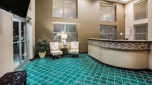 A reception area with a curved counter, two chairs, a potted plant, and a bench. - Super 8 by Wyndham Sevierville Riverside (Sevierville)