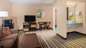 A hotel room with a sofa, TV, desk, chair, and a mirror. - Super 8 by Wyndham Sevierville Riverside (Sevierville)