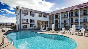 A hotel with a swimming pool, outdoor seating, and a multi-story building with balconies. - Super 8 by Wyndham Sevierville Riverside (Sevierville)