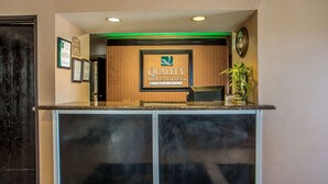 Una mesa de recepción con un cartel enmarcado que dice "Quality Inn & Suites by Choice Hotels".