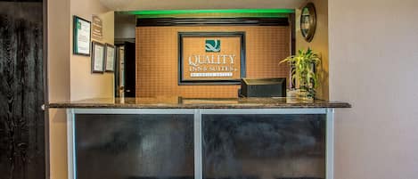 Una mesa de recepción con un cartel enmarcado que dice "Quality Inn & Suites by Choice Hotels".