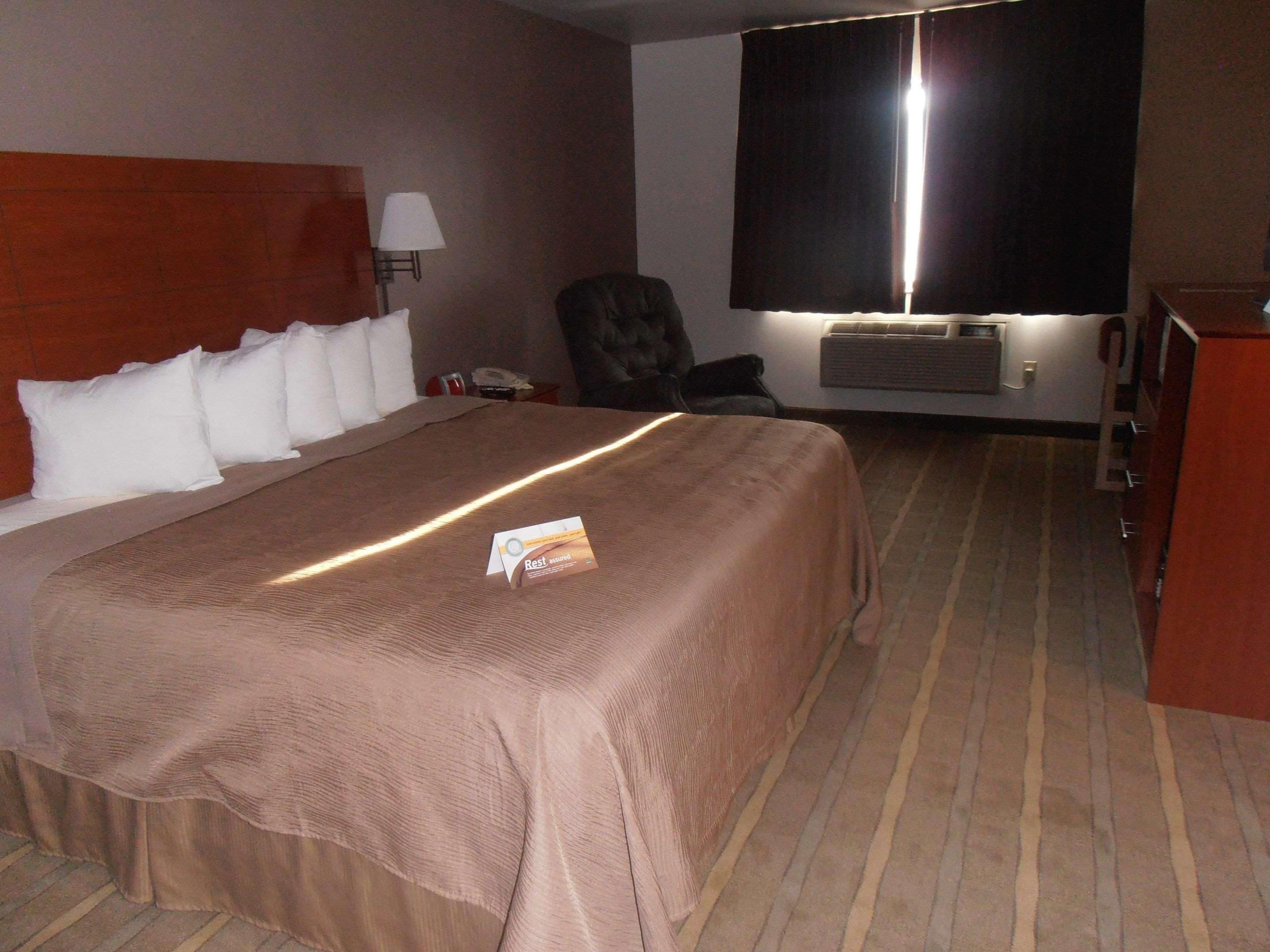 Habitación de hotel con una cama grande, una silla, un escritorio y un televisor.