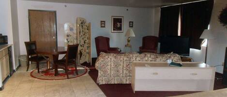 A room with a bed, a sofa, a desk, and a television.