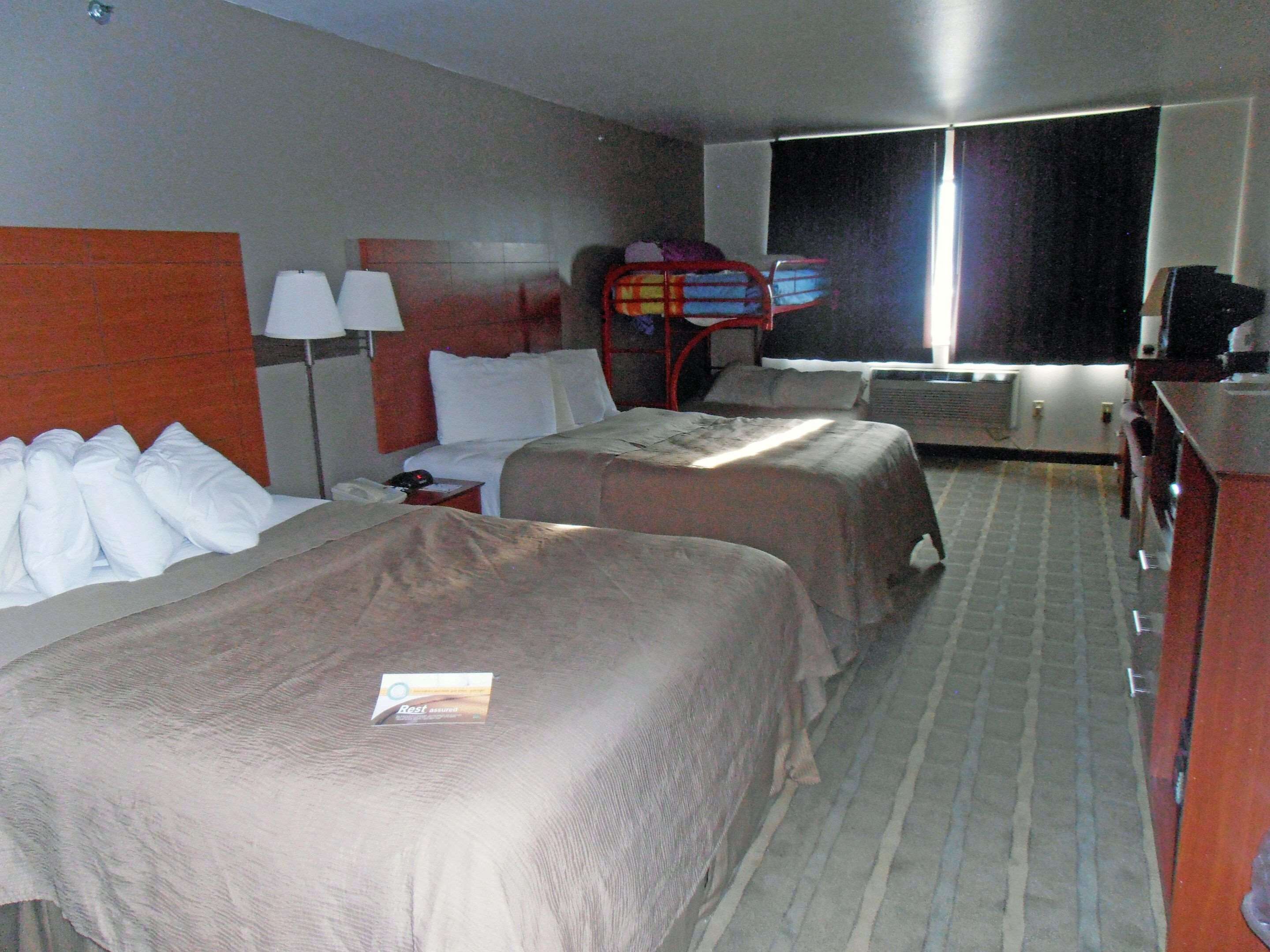 Una habitación de hotel con dos camas, un escritorio, una silla, un televisor y una ventana.