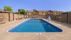 Une piscine rectangulaire dont la profondeur maximale est indiquée à 5 pieds, entourée d’une clôture et avec un bâtiment doté de nombreuses fenêtres en arrière-plan.