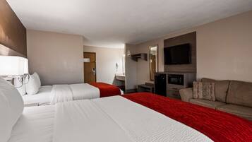 A hotel room with two beds, a sofa, a TV, a microwave, and a small desk.