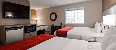 A hotel room with two beds, a TV, a desk with a chair, a microwave, and a window with a view.