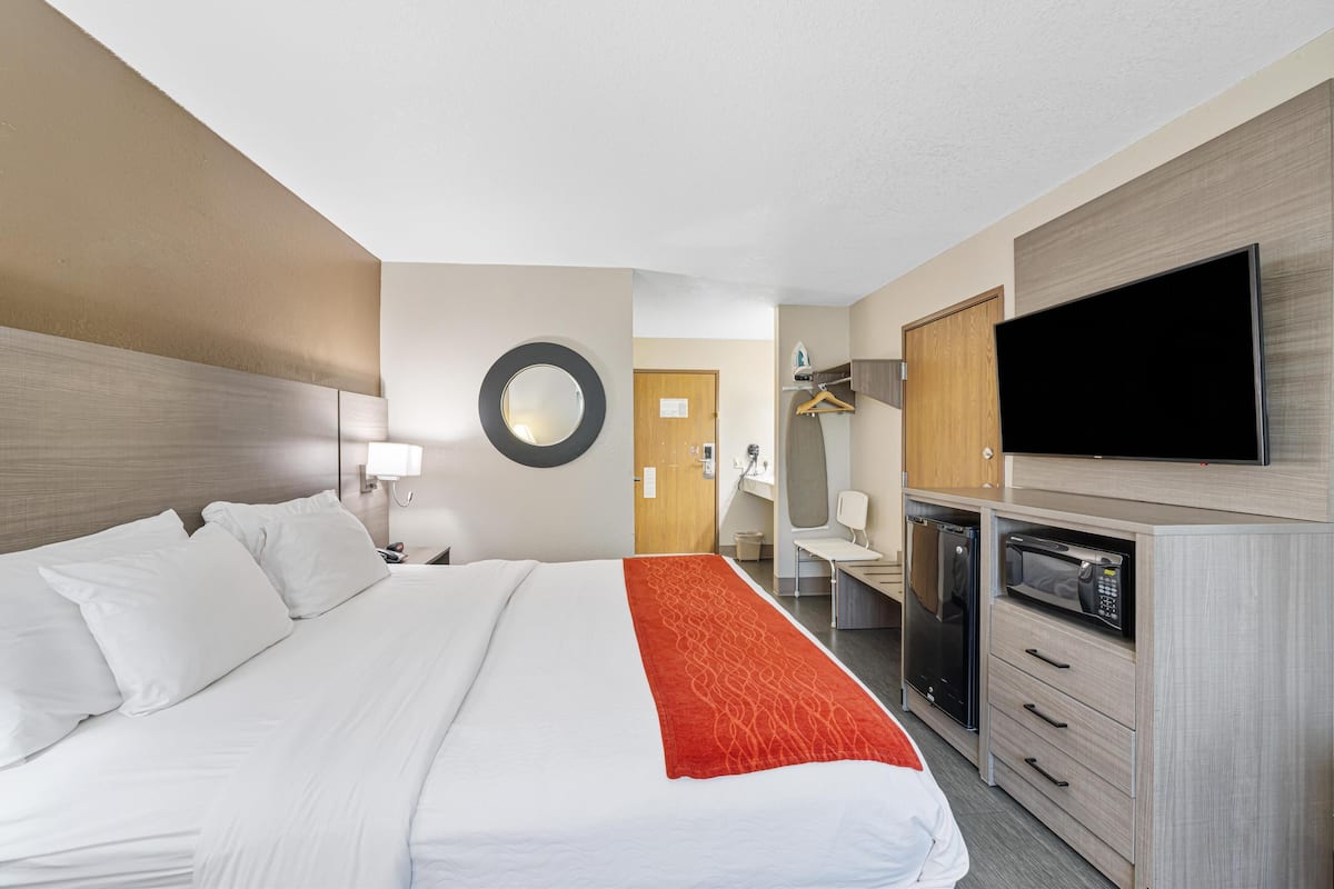 Ein Hotelzimmer mit einem großen Bett, einem Flachbildfernseher, einer Mikrowelle und einem Schreibtisch mit Stuhl.