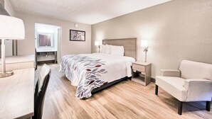 A hotel room with a bed, bedside tables, a chair, a desk, and a mirror.