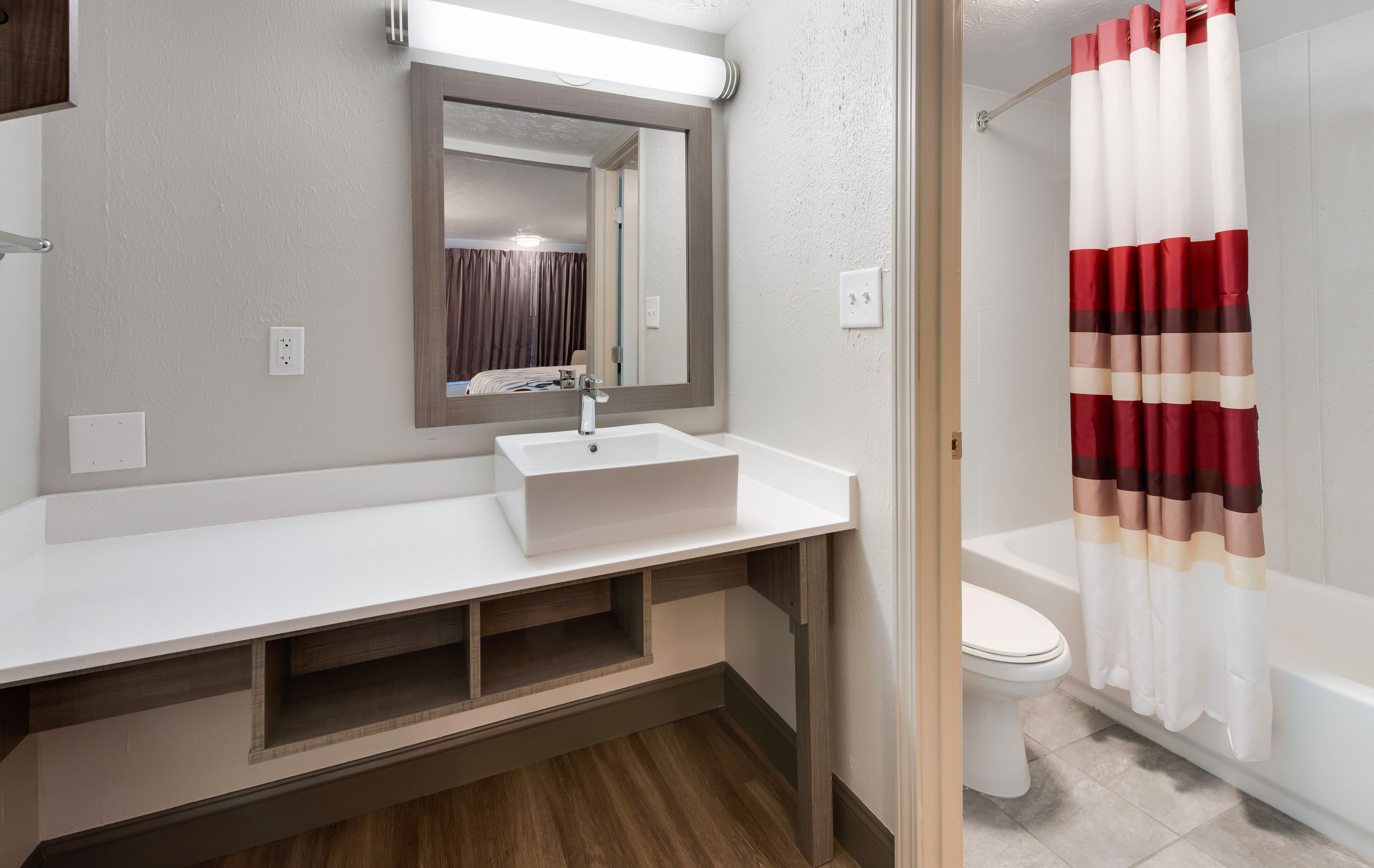 A modern bathroom with a white sink, mirror, and a shower curtain with a striped pattern.