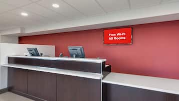 Una reception con parete rossa e cartello che indica Wi-Fi gratuito in tutte le camere.