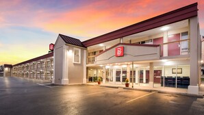 A Red Roof Inn with a two-story structure, a parking lot, and a sunset sky. - Red Roof Inn Dayton - Moraine/U of Dayton (Moraine)