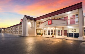 A Red Roof Inn with a two-story structure, a parking lot, and a sunset sky. - Red Roof Inn Dayton - Moraine/U of Dayton (Moraine)