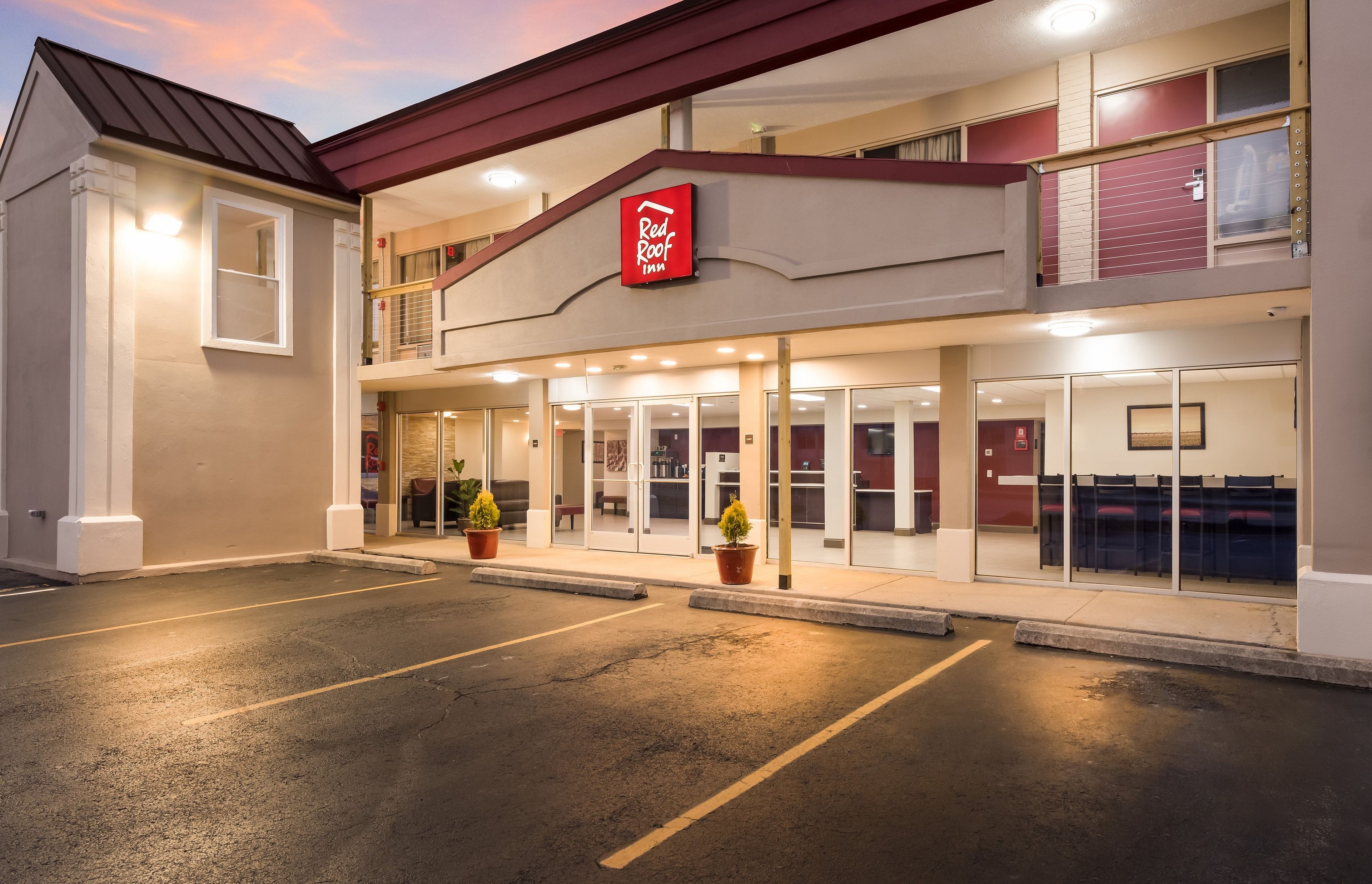 A Red Roof Inn with a two-story structure, a parking lot, and a clear sky.