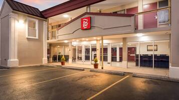A Red Roof Inn with a two-story structure, a parking lot, and a clear sky.
